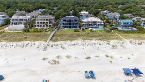A beachfront property with multiple houses, a sandy beach, and a pier. - 11 Sea Hawk Lane - Oceanfront Oasis: Stylish Coastal Living & Endless Views (Hilton Head Island)