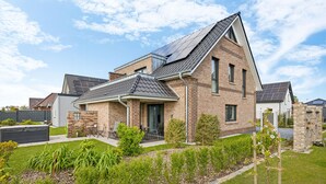 Ein modernes, zweistöckiges Haus mit Satteldach, Backsteinfassade und Solaranlage.