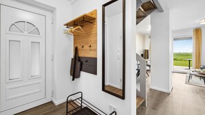Ein modernes Interieur mit einer Holzwandverkleidung, einem großen Spiegel und einer Metallbank.