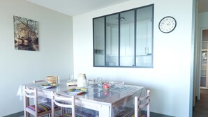 Un coin repas avec une table en verre, des chaises et une horloge au mur.