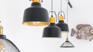 A series of pendant lights with black and gold fixtures, a fish mural on the wall, and a partially visible mesh light fixture.