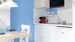 A modern kitchen with white cabinets, a microwave, and a coffee machine.
