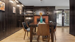 Ein Essbereich mit Holztisch, Stühlen, einem Deckenventilator und einem Kamin aus Ziegelsteinen.