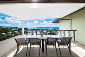 Ein Balkon mit Tisch und Stühlen, Blick auf das Meer und einer Geländer.