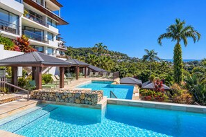 A resort with a pool area, multiple levels of balconies, and lush greenery.