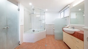 Casa de banho moderna com chuveiro de vidro, banheira, toucador com lavatório e um espelho grande.