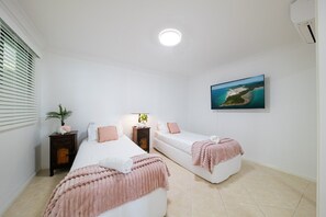 A bedroom with two beds, a nightstand, a lamp, and a painting on the wall.