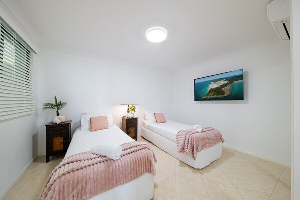 Un dormitorio con dos camas, una mesita de noche, una lámpara y un cuadro en la pared.
