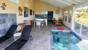 A spacious indoor area with a kitchen, dining area, and a glass-enclosed pool. - Magnifique Loft Avec vue Imprenable sur la mer (Grand-Bourg)