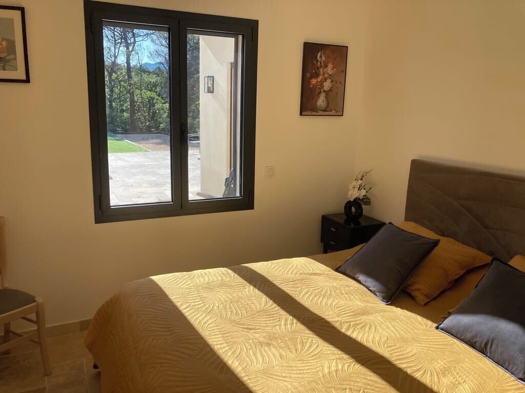 Una camera da letto con un letto, un comodino, una sedia e una finestra vista all'esterno.