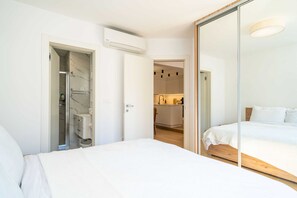A bedroom with a large bed, a walk-in closet, and a visible bathroom with a shower.