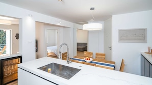 Eine moderne Küche mit einer großen Kochinsel, Backofen und einem Essbereich mit Holzküchenmöbeln.