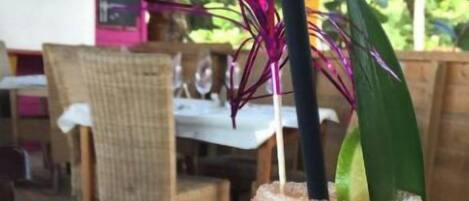 A table with a drink in a glass, a small glass with a lime, and cutlery.
