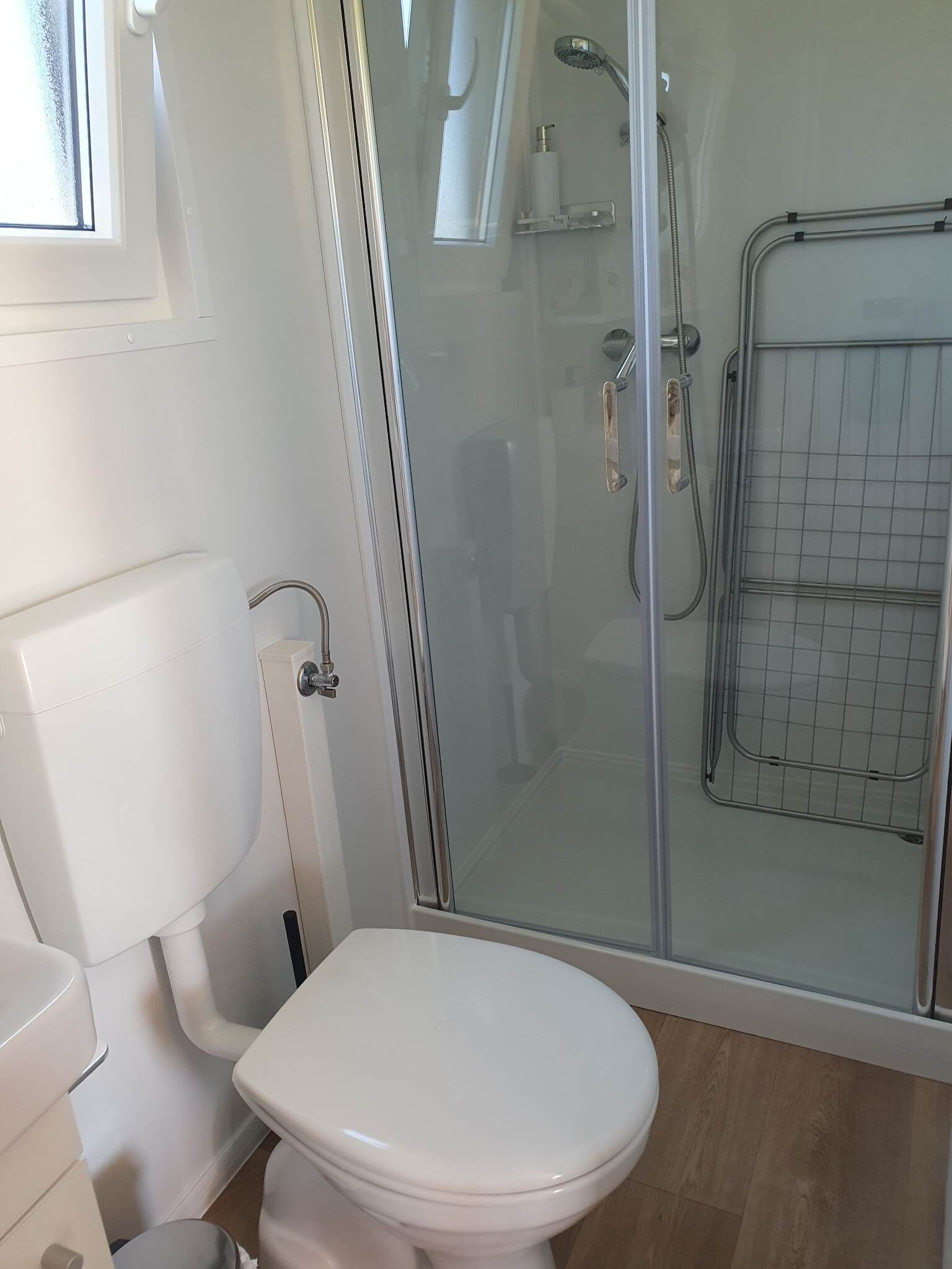 Ein Badezimmer mit Toilette, Duschkabine aus Glas und weißem Toilettenpapierhalter.