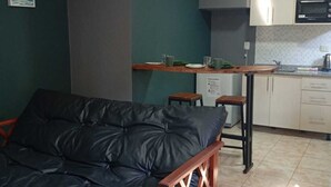 Un ambiente compatto con divano, angolo cottura e tavolo da pranzo.