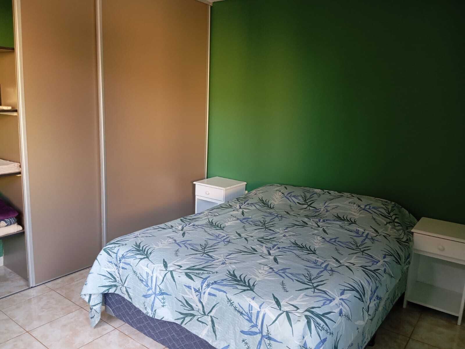 Une chambre à coucher avec un lit, une table de chevet et une armoire.