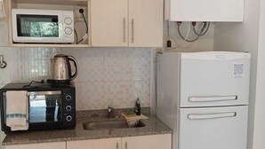 A compact kitchen with a microwave, toaster, kettle, and refrigerator. - LAS PALMAS VILLAGE (Puerto Iguazú)