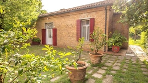 Una casa in mattoni con tetto in tegole, un'entrata e un piccolo giardino con piante in vaso.