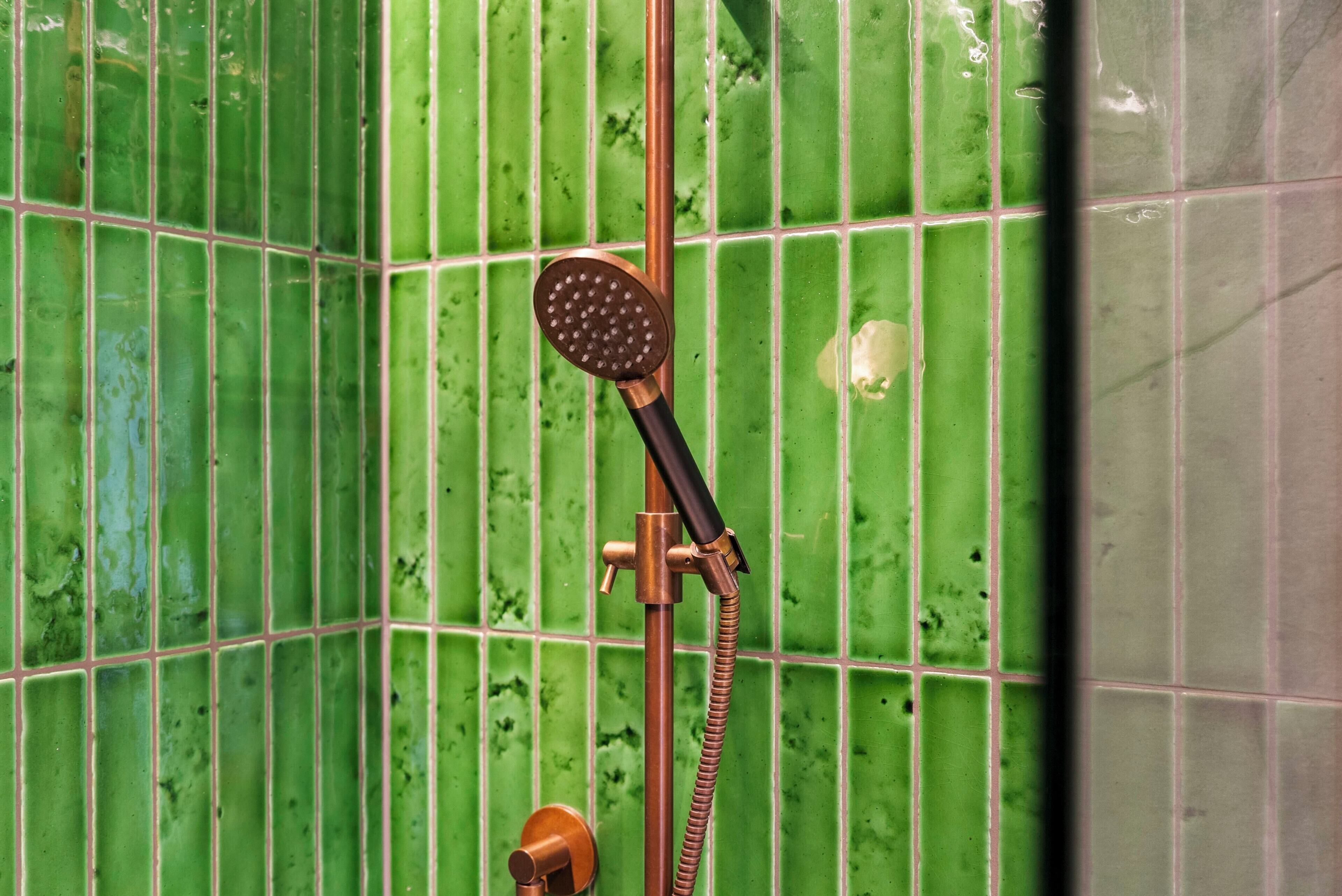 Een douche met een handdouche en een bedieningskraan aan de muur.