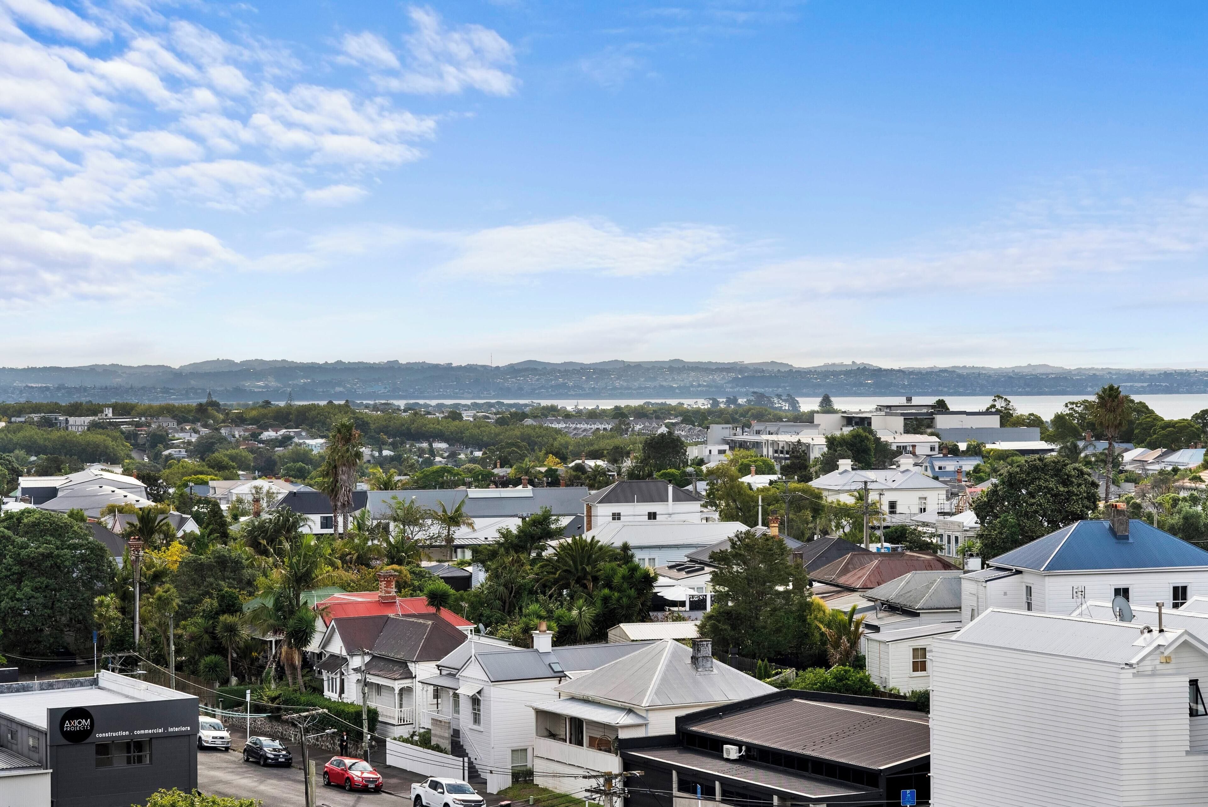 A residential area with houses, streets, and a distant view of a city skyline.