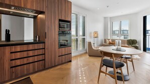 Eine moderne Küche mit Holzausstattung, einer eingebauten Mikrowelle und einem Essbereich mit rundem Tisch und Stühlen.