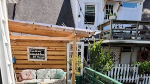 A wooden deck with a round table and chairs, a wooden pergola, and a white picket fence. - Family Hideaway ,family friendly and pet friendly. (Virginia Beach)