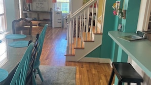 A spacious kitchen with a dining area, wooden floors, and a staircase leading to another level. - Family Hideaway ,family friendly and pet friendly. (Virginia Beach)