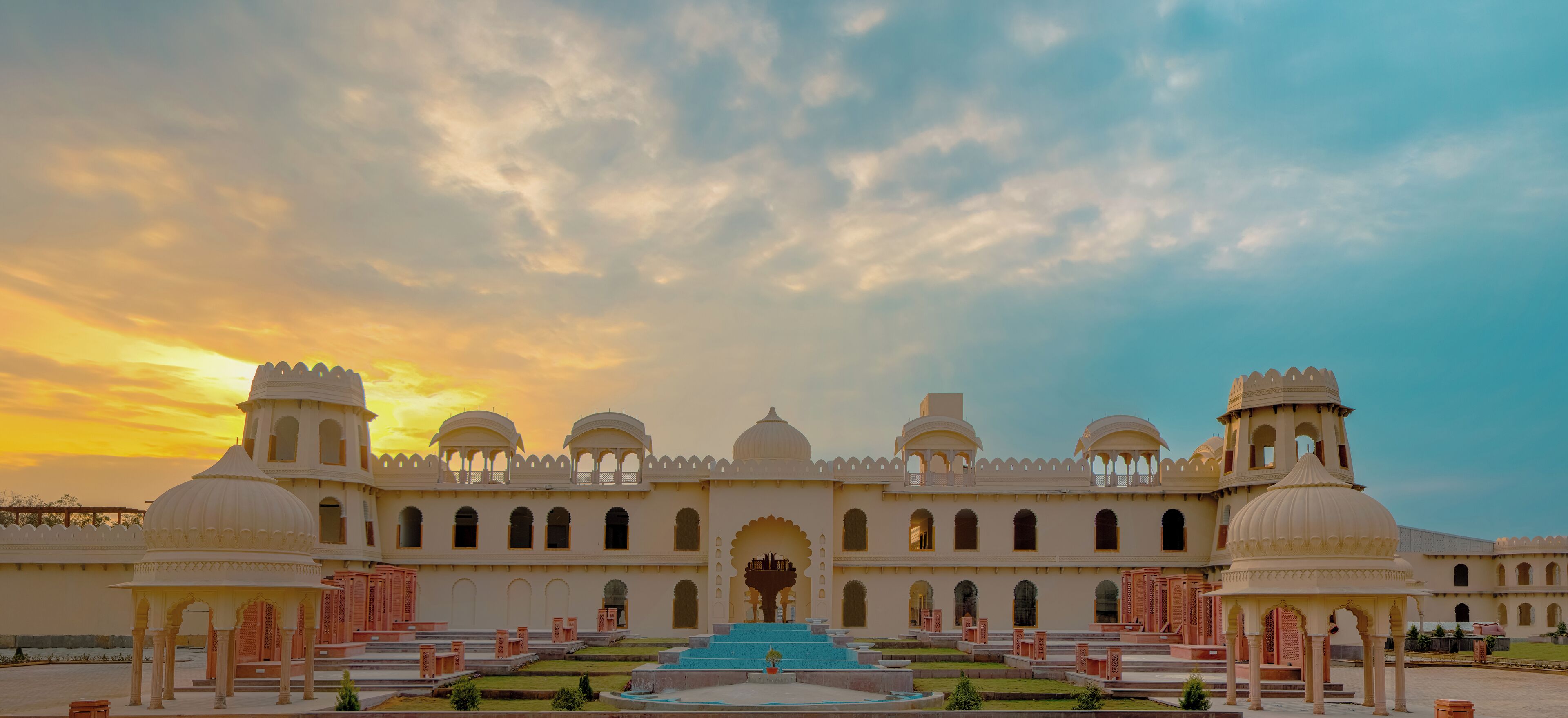 A grand building with multiple domes and arches, a central fountain, and a symmetrical garden layout.