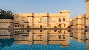 A traditional building with a reflection in a pool, featuring arched windows and a balcony. - Kesarbagh Palace (Chittorgarh)