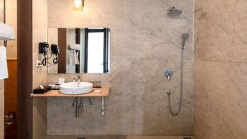 Une salle de bain moderne avec un sol en marbre, une grande baignoire, un lavabo avec un miroir, une douche et un luminaire au plafond.