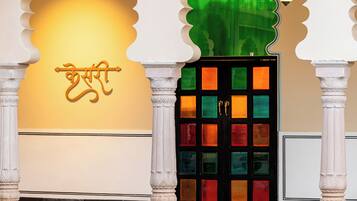 Un edificio tradicional con un amplio arco de entrada, una pared decorativa con un emblema dorado y una puerta colorida con un panel de vidrio verde.