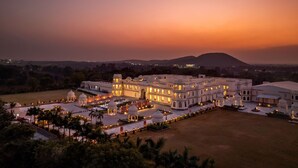 A large, illuminated hotel with multiple domes and arches, set against a sunset backdrop. - Kesarbagh Palace (Chittorgarh)