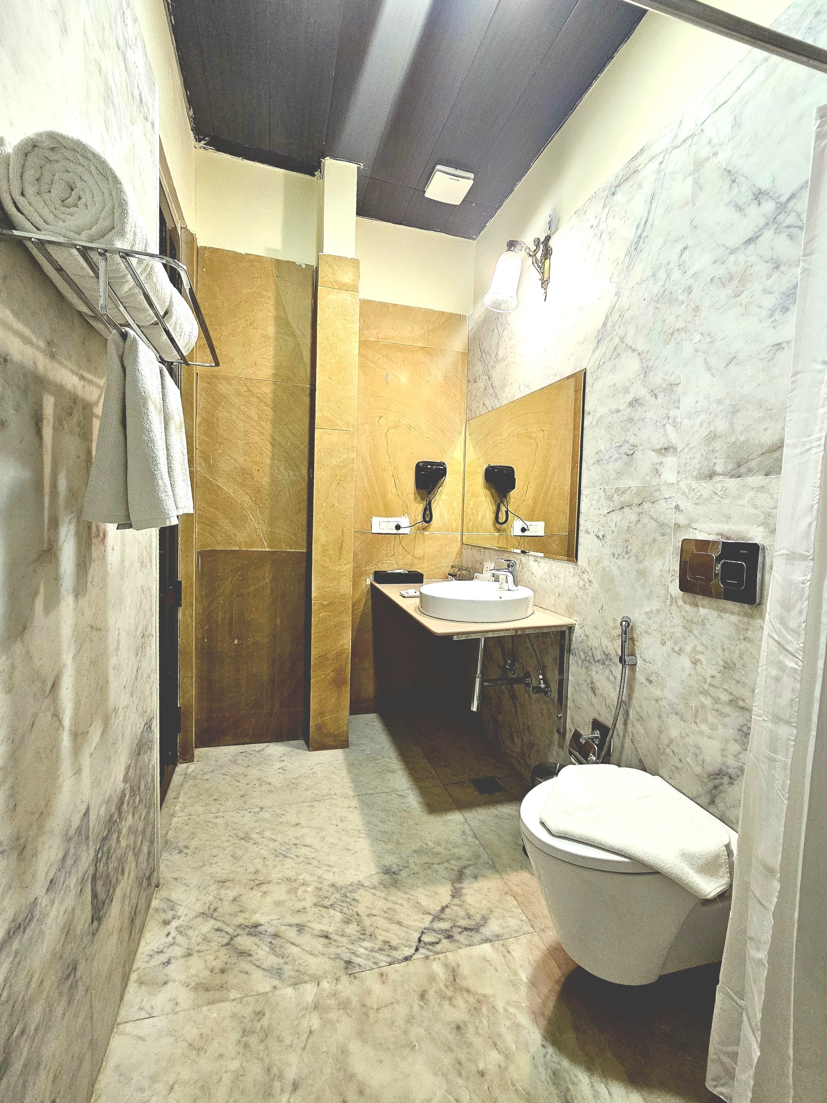 Un bagno con pavimento in marmo, un water, un lavandino e una doccia.