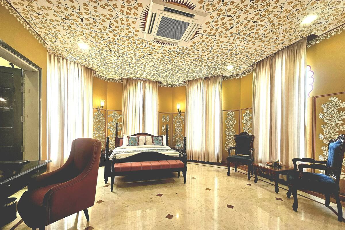 Habitación de hotel con una cama grande, dos sillas, un escritorio y un espejo.
