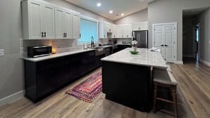 Una cocina moderna con armarios blancos, una encimera de granito y un refrigerador de acero inoxidable.