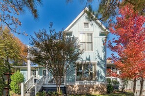 A two-story house with a front porch, a staircase, and a brick foundation.
