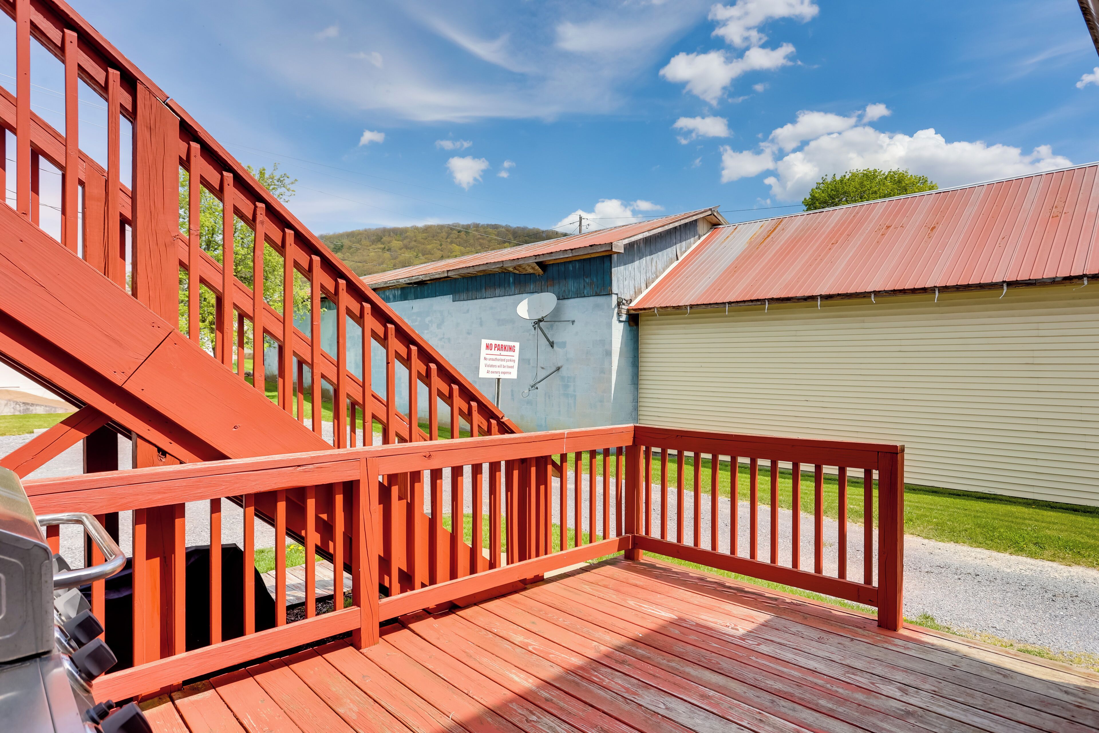 A wooden deck with a red railing, a satellite dish on a building, and a 'No Parking' sign.