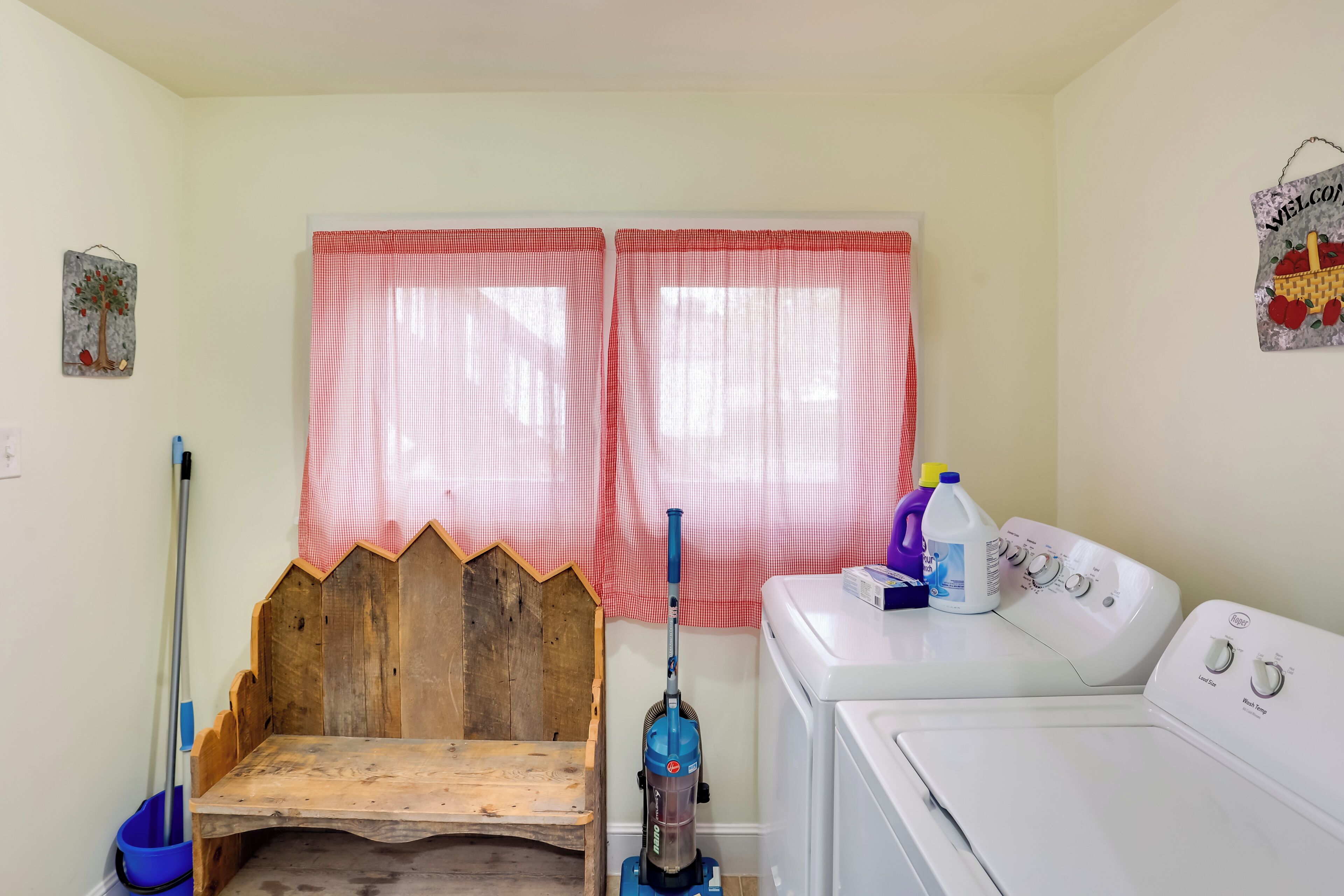 A laundry room with a washing machine, a vacuum cleaner, and a mop.