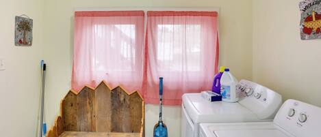 A laundry room with a washing machine, a vacuum cleaner, and a mop.