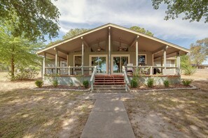A two-story building with a covered porch, a staircase leading to the entrance, and a clear sky. - Yard, Deck & Fire Pit: Cedar Creek Reservoir Gem (Mabank)