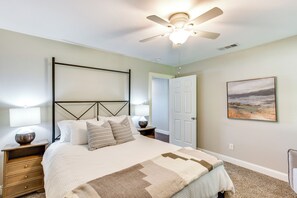 A bedroom with a bed, nightstands, a ceiling fan, a door, and a painting on the wall. - Yard, Deck & Fire Pit: Cedar Creek Reservoir Gem (Mabank)