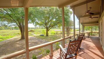 A covered outdoor area with wooden deck seating and a view of a green landscape.