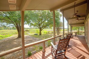 A covered outdoor area with wooden deck seating and a view of a green landscape. - Yard, Deck & Fire Pit: Cedar Creek Reservoir Gem (Mabank)