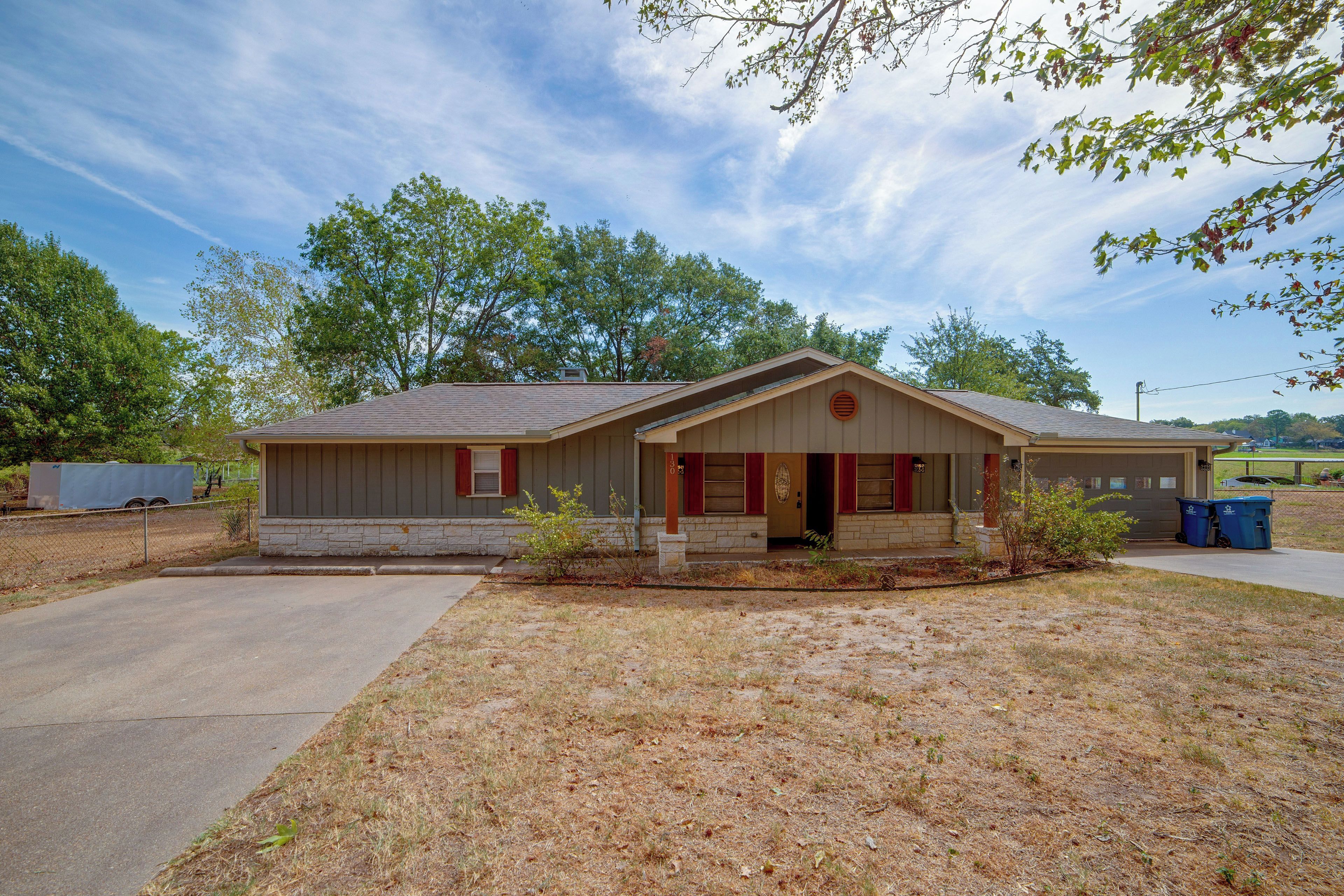 A single-story house with a front porch, a garage, and a small yard.
