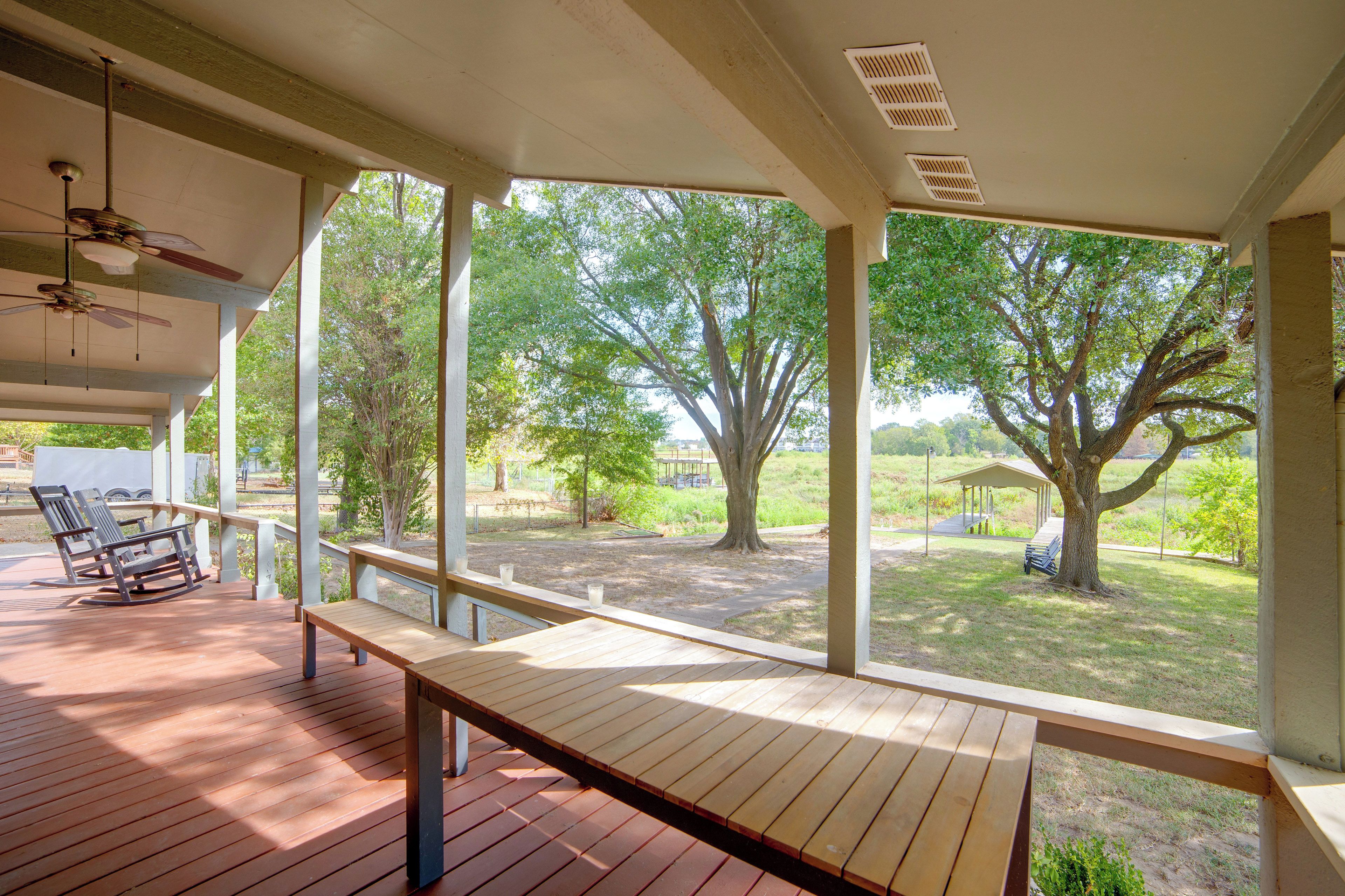 A covered outdoor area with a wooden deck, benches, and a ceiling fan.