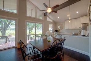 A spacious dining area with a wooden table and chairs, large windows, and a ceiling fan. - Yard, Deck & Fire Pit: Cedar Creek Reservoir Gem (Mabank)
