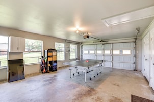 A garage with a ping pong table, a ceiling fan, and a garage door.