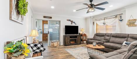 Ein Wohnzimmer mit Sofa, Fernseher, Kamin und Zierpflanzen.