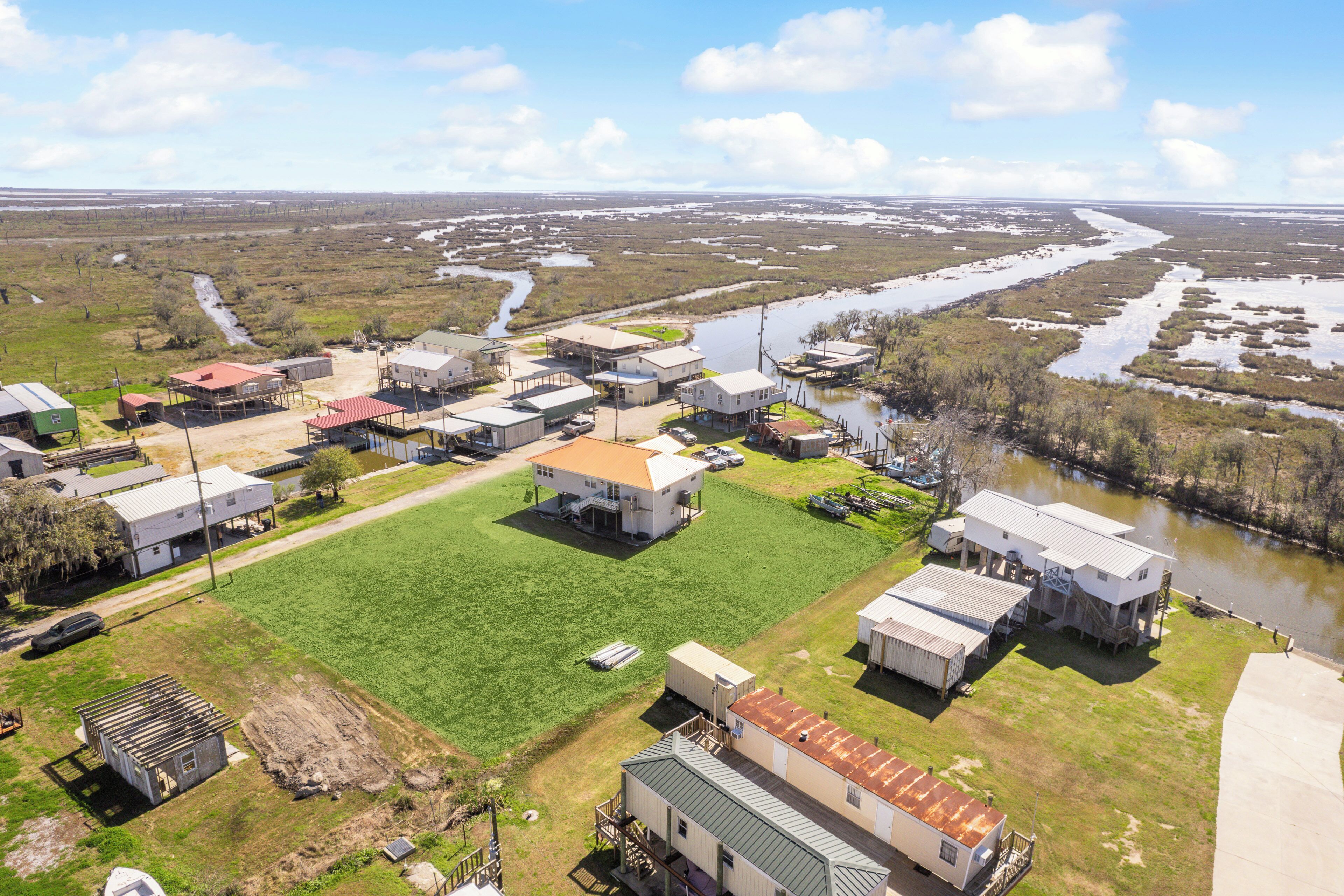 Vista aérea de una zona residencial con casas, un río y un campo verde extenso.