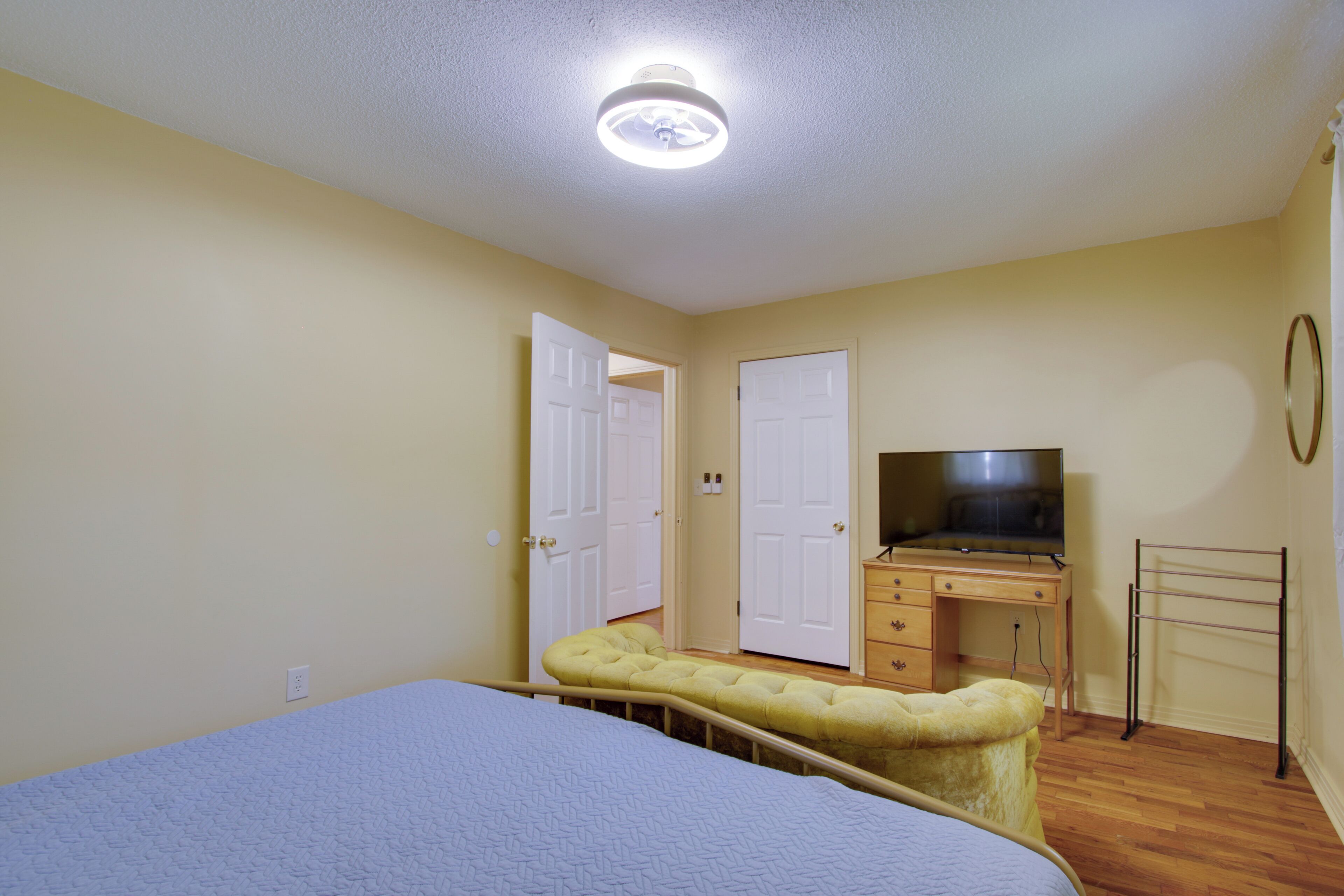 A bedroom with a bed, a dresser, a television, and a door.